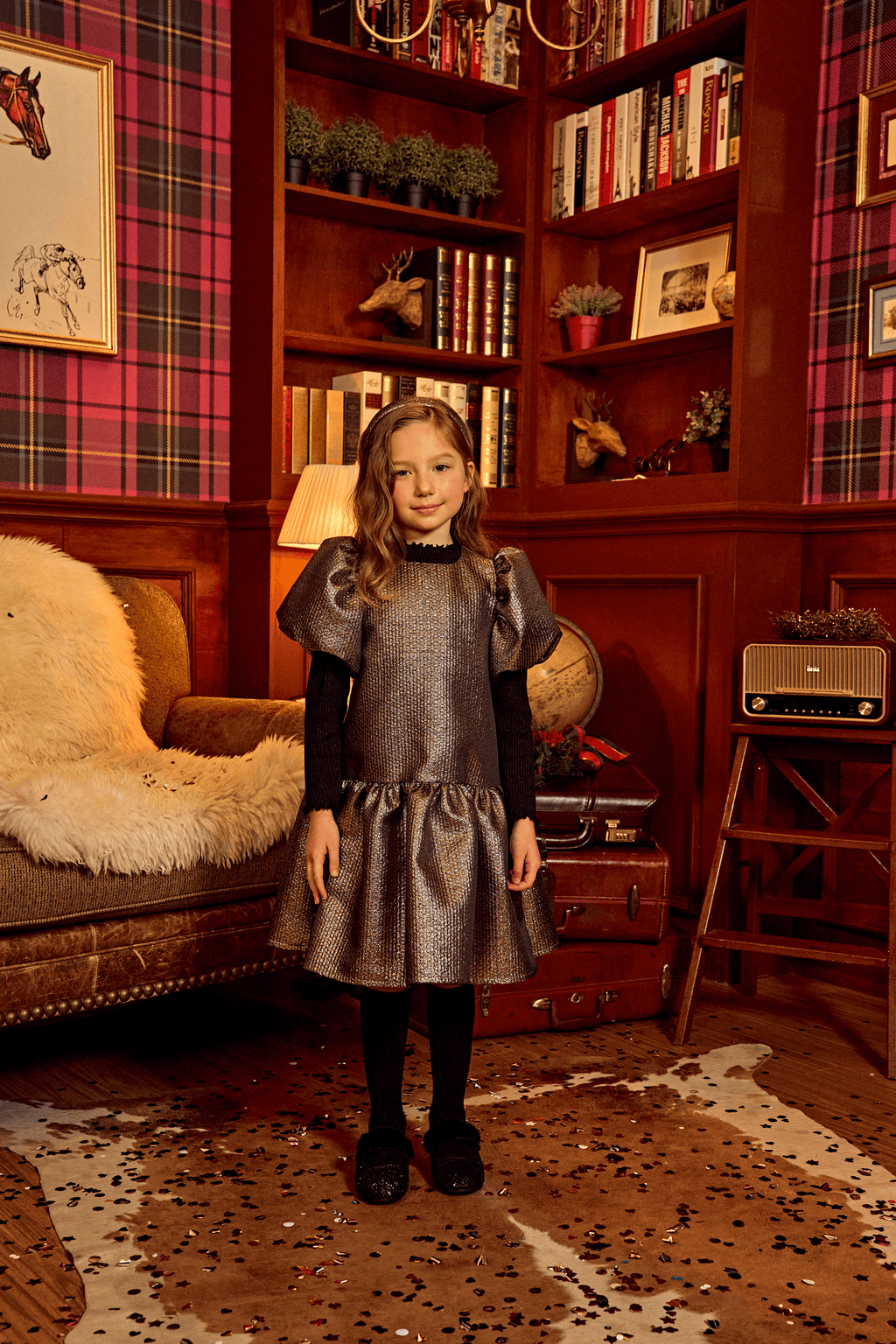 Girl wearing a light gold Selena Jacquard Balloon Dress in a cozy, vintage-style room with bookshelves and decorative items.