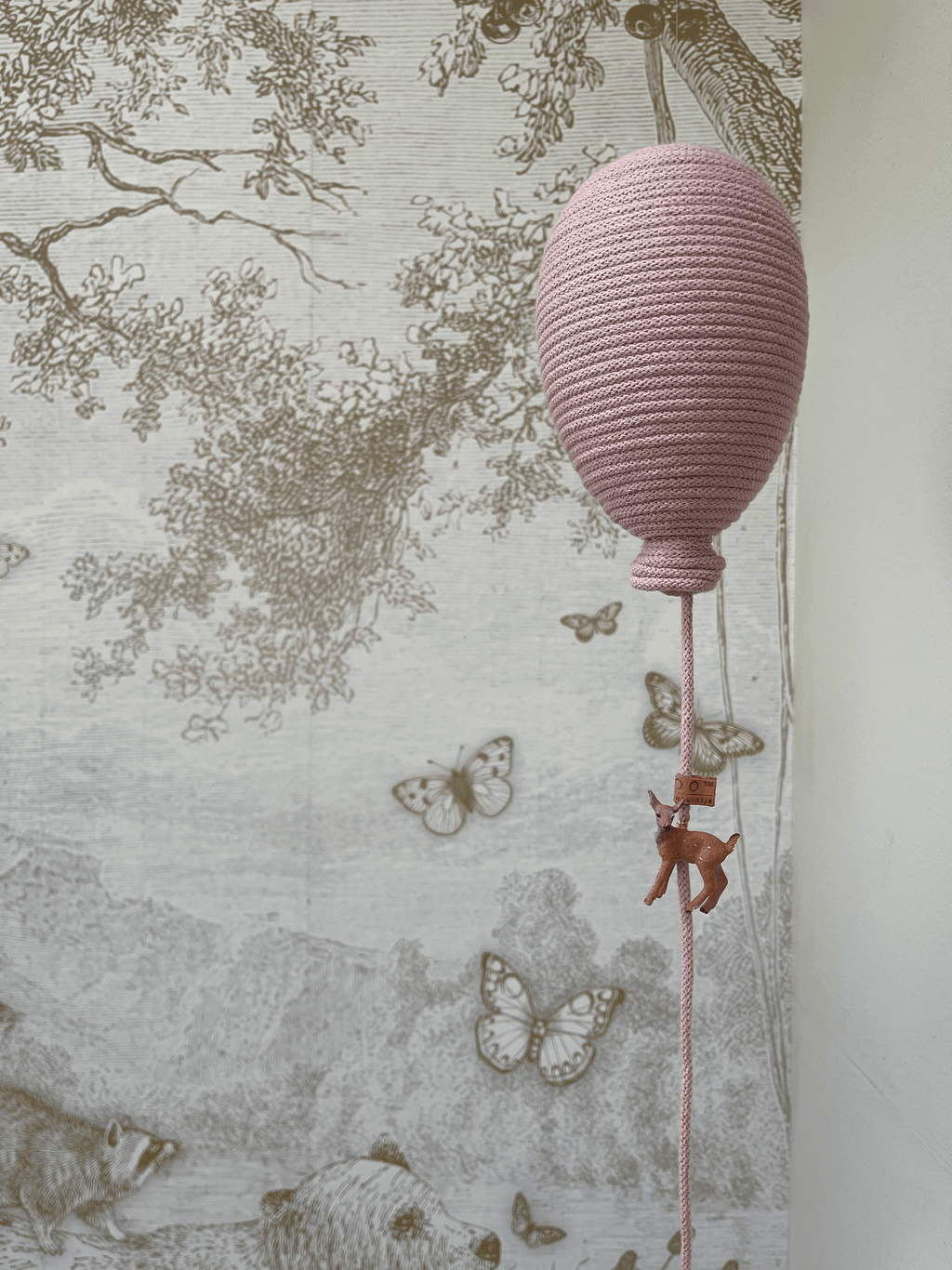 Powder pink hot air balloon decoration for baby nursery décor hanging with butterflies in the background.