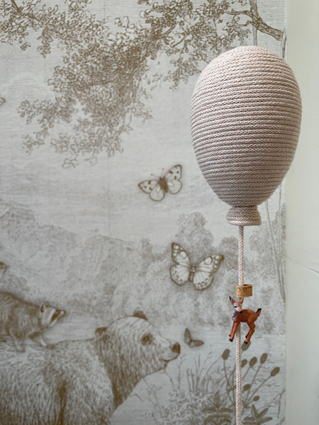 Beige hot air balloon decoration with deer charm against nature-themed wallpaper, perfect for baby room or gender reveal decor.