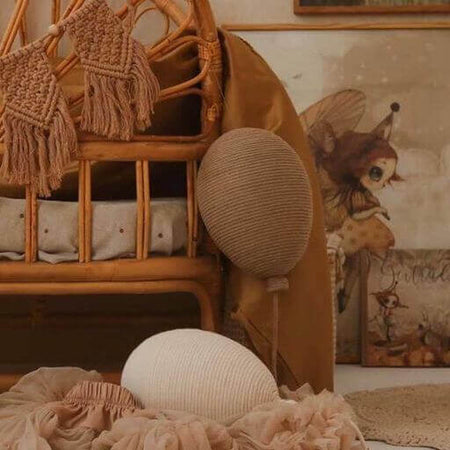 Cozy nursery with caramel and cream hot air balloon decor, wicker crib, and whimsical artwork, perfect for baby room decoration.